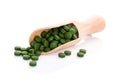 Green pills on wooden scoop.