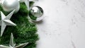 Green pine tree leaves on white marble background, christmas decorations in bright silver color. Simple and creative christmas con Royalty Free Stock Photo