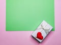 Green and pink background with a gift box and a heart with space for text