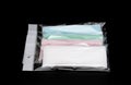 Green, pink, light blue and white ear loop disposable face mask in plastic bag overlapping, used for covering mouth and nose.