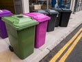 Green and pink recycling bins and normal black general waste refuse bins.