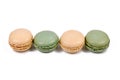 Green pistachio and yellow vanilla French macarons in a row on white background