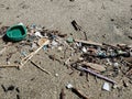 Green plastic bottle cork on sandy sea coast, polluted ecosystem,microplastics Royalty Free Stock Photo