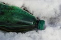 Green plastic bottle trash on white snow Royalty Free Stock Photo