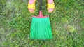 Green plastic broom on the grass and women`s feet in yellow rubber flip flops. top view. Creative cleaning concept. Garden, cleanl Royalty Free Stock Photo