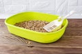 Green plastic cat litter box with wooden pellets and scoop on a brown wooden floor. New cat toilet tray near the wall. Toilet for Royalty Free Stock Photo