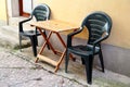 Green plastic chairs and wooden table outdoor in front of house on terrace and street / Arrangement of Desk and chair. Royalty Free Stock Photo