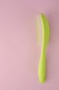 Green plastic comb for hair on pink background. Royalty Free Stock Photo