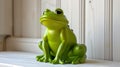 Green plastic frog figurine placed on a white shelf indoors. Royalty Free Stock Photo