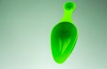 Green plastic measuring spoon isolated on gradient grey-white background with copy space Royalty Free Stock Photo