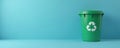 Green plastic recycle bin with white recycle symbol rests on blue surface. Empty container provides ample copy space for eco Royalty Free Stock Photo