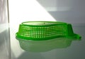 Green plastic strainer on glass surface with reflections. blurred background Royalty Free Stock Photo