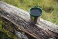 Green plastic thermos stainless steel cup put on a log on sunny day Royalty Free Stock Photo