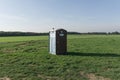 Green plastic toilet in the middle of an empty green field