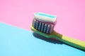 Green plastic toothbrush with striped toothpaste on a pink blue table Royalty Free Stock Photo
