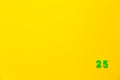 A green plastic toy number twenty five is located in the lower right corner on a yellow background Royalty Free Stock Photo