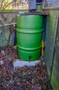 Green plastic water butt in the corner of the garden