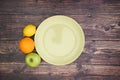 Green plate apple orange and lemon on wooden table Royalty Free Stock Photo