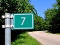 7 KM travelled distance road sign in green plate. mileage sign. red van in a distance Royalty Free Stock Photo