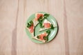 Green plate with salmon sandwiches with butter and parsley on wooden table. Buffet breakfast lunch meal. Healthy eating. Fish diet
