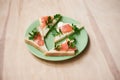 Green plate with salmon sandwiches with butter and parsley on wooden table. Buffet breakfast lunch meal. Healthy eating. Fish diet