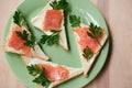 Green plate with salmon sandwiches with butter and parsley on wooden table. Buffet breakfast lunch meal. Healthy eating. Fish diet