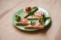 Green plate with salmon sandwiches with butter and parsley on wooden table. Buffet breakfast lunch meal. Healthy eating. Fish diet
