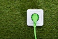 Green plug in outlet on grass Royalty Free Stock Photo
