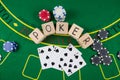 On a green poker table are cards, chips and the inscription poker on wooden cubes Royalty Free Stock Photo