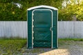 A Green Portable Plastic Toilet in a Park for events.