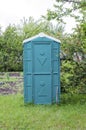 Green portable plastic toilet .Transportable modern designed street toilet is placed atcountry cottage area, outdoor privacy
