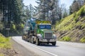 Green powerful big rig semi truck with oversize load yellow sign on the roof transporting crawler on the step down semi trailer