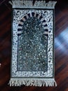 Green prayer rug placed on parquet floor