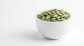 Fresh green pumpkin seeds filling a white bowl, placed on a gray background, representing healthy eating and natural Royalty Free Stock Photo