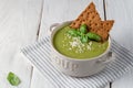 Green puree soup with rye crisps, sesame seeds and basil in a plate