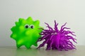 A green and a purple gummy ball both with eyes as a representation of virus or bacteria