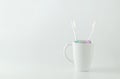 Green and purple toothbrush with white ceramic mug on white back Royalty Free Stock Photo