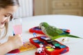 The green quaker parrot is posing on paints for a little girl Royalty Free Stock Photo
