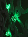 Green Rattan ball garland on patterned wall. Christmas and New Year led lights on dark background. Blurred glowing light bulb Royalty Free Stock Photo