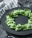 Green ravioli with spinach and ricotta cheese on plate over dark holiday background with glass of wine. Merry Christmas and New Royalty Free Stock Photo