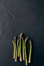 Green raw asparagus spears on black slate background. Concept of healthy food and crop of spring vegetables. Close up Royalty Free Stock Photo