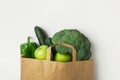Green raw organic vegetables fruits broccoli cucumbers bell peppers apples in brown Kraft paper grocery bag on white background Royalty Free Stock Photo