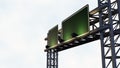 Green rectangular signboard with silver trim, fixed to a metal overhead steel structure