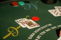 Green rectangular table with a variety of playing cards and poker chips scattered in a casino