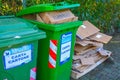 A scene of recycling in Europe: green trash containers overfilled with cardboard and paper. Bad waste manegment in Italy