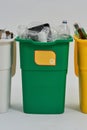 Green recycle garbage bin with recycle sign on it full of rubbish standing in a row with other bins isolated on white Royalty Free Stock Photo
