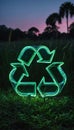 Green recycle symbol made of translucent glass set against lush verdant landscape