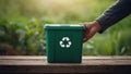 Green Recycling Bin on Wooden Table with Blurred Nature Background Royalty Free Stock Photo