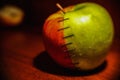 Green and red apple stapled with two halves Royalty Free Stock Photo