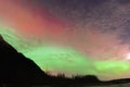 Green and Red Aurora Over Mountains and Trees